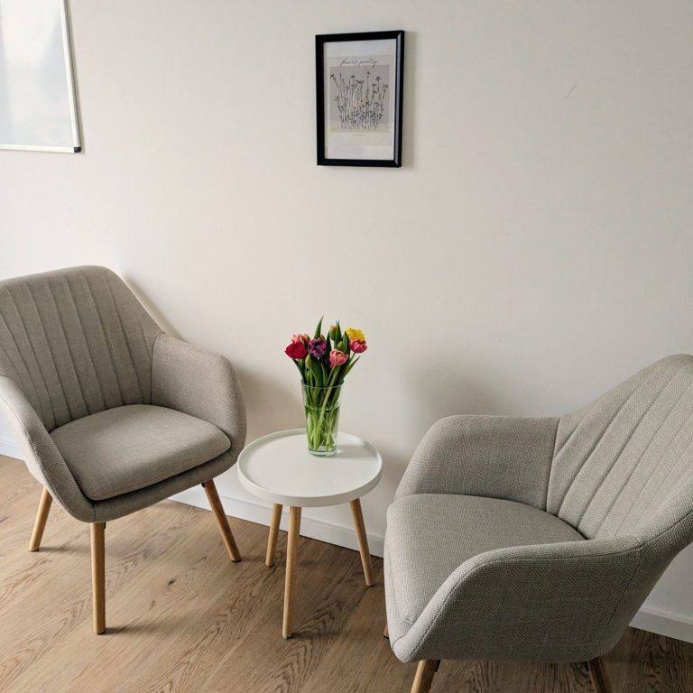 Zwei bequeme Sessel neben einem kleinen Tisch mit einem Blumenstrauß.