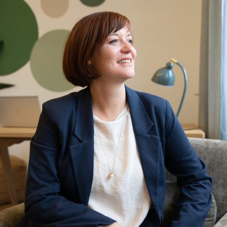 Portrait Birgit Gebauer in einem modernen Büro, lächelnd und nachdenklich.